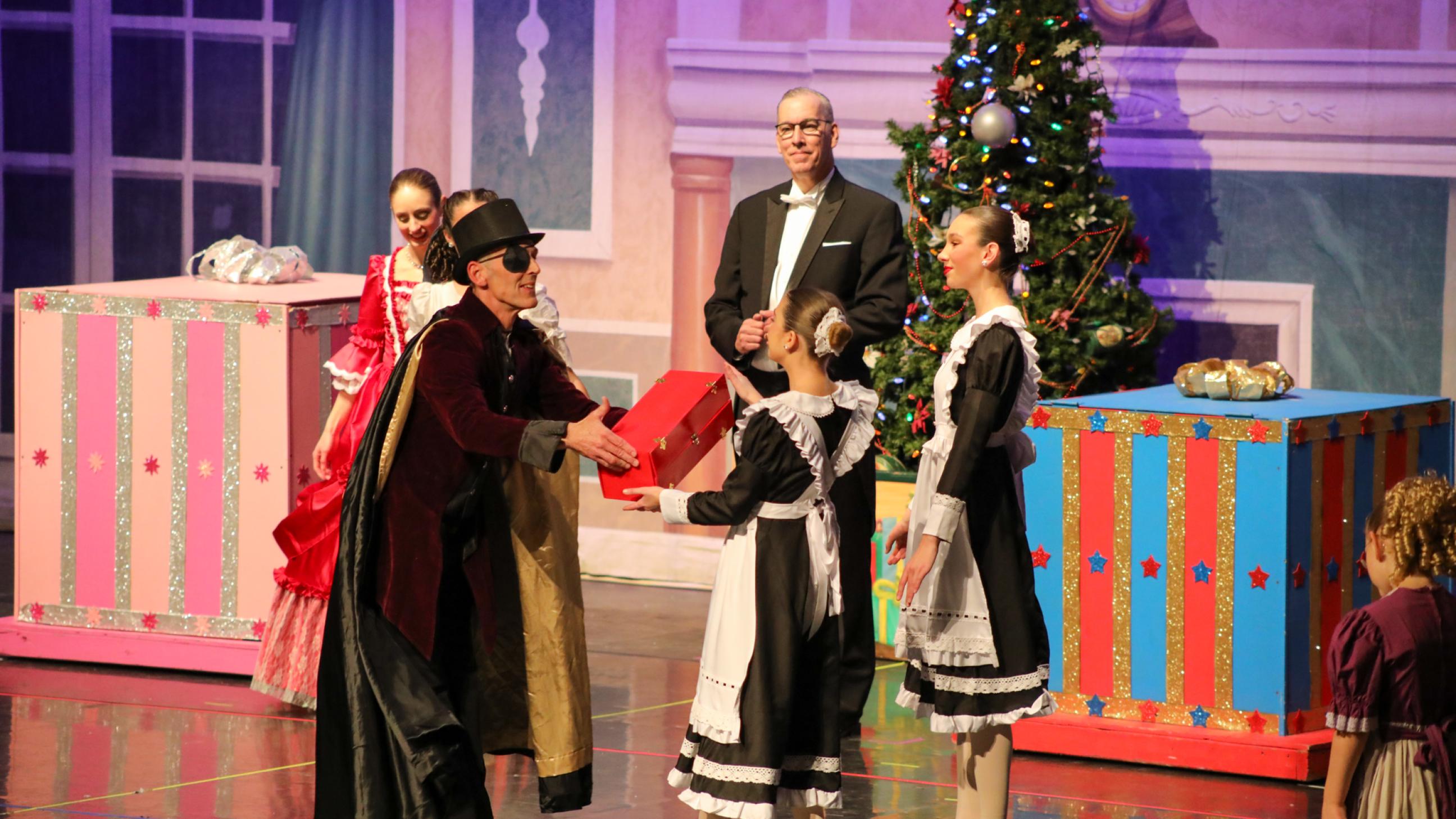 Drosselmeyer hands gift to the maid